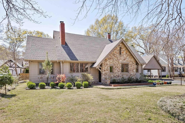 view of front of property with a front lawn, a chimney, a shingled roof, and stone siding