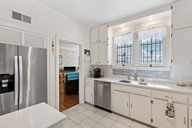 kitchen with light countertops, a sink, appliances with stainless steel finishes, light tile patterned floors, and visible vents