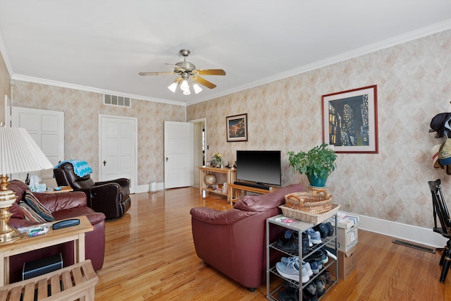 living area with visible vents, baseboards, ceiling fan, wood finished floors, and wallpapered walls