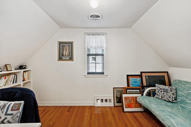 bedroom featuring baseboards, visible vents, wood finished floors, and vaulted ceiling