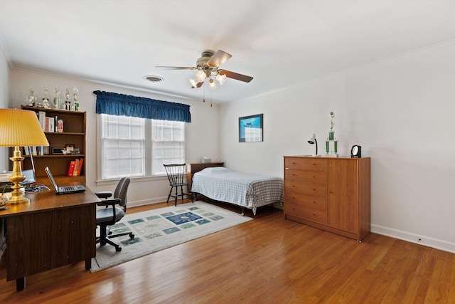 bedroom featuring baseboards, visible vents, wood finished floors, and ornamental molding