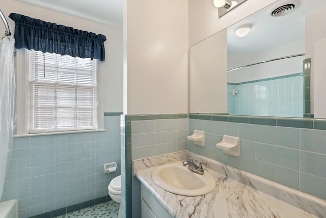 bathroom with tile walls, visible vents, toilet, and a shower