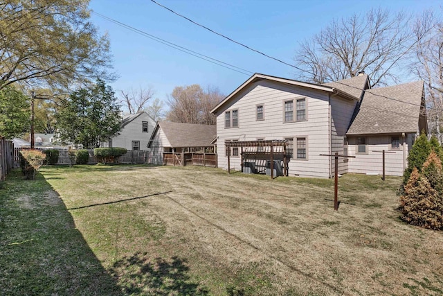 rear view of property featuring a fenced backyard, a shingled roof, and a yard