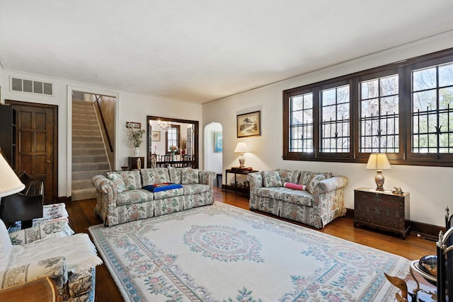 living area featuring baseboards, stairs, visible vents, and wood finished floors