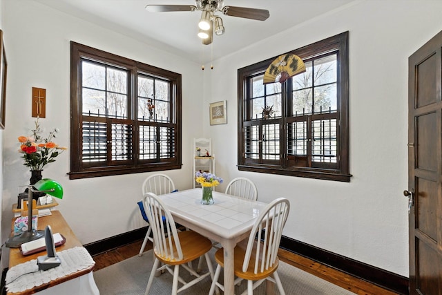 dining space featuring baseboards, ceiling fan, and wood finished floors