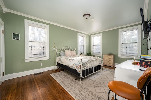 bedroom featuring wood finished floors, crown molding, baseboards, and visible vents
