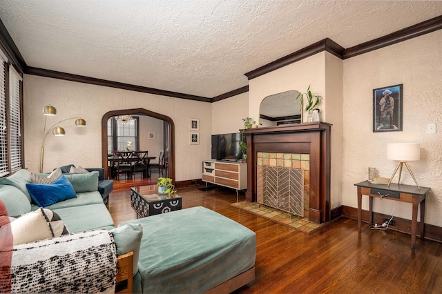 living area featuring a textured ceiling, ornamental molding, wood finished floors, arched walkways, and a textured wall