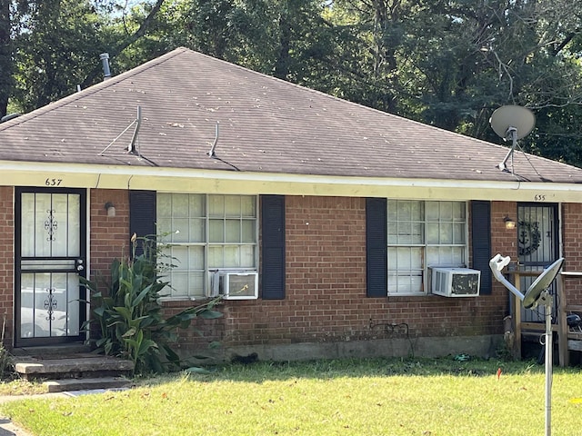 view of front of home featuring a front lawn, a shingled roof, cooling unit, and brick siding