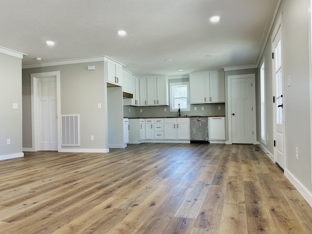 kitchen with crown molding, a sink, dishwasher, dark countertops, and visible vents