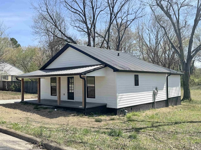 view of side of property featuring fence, metal roof, and a porch