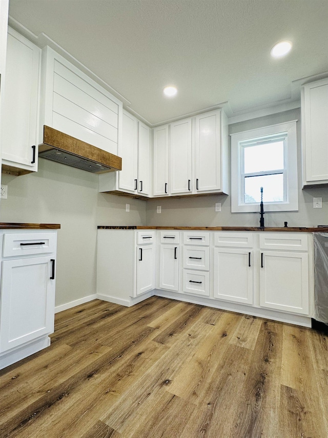 kitchen featuring white cabinetry, recessed lighting, baseboards, dark countertops, and light wood-style flooring