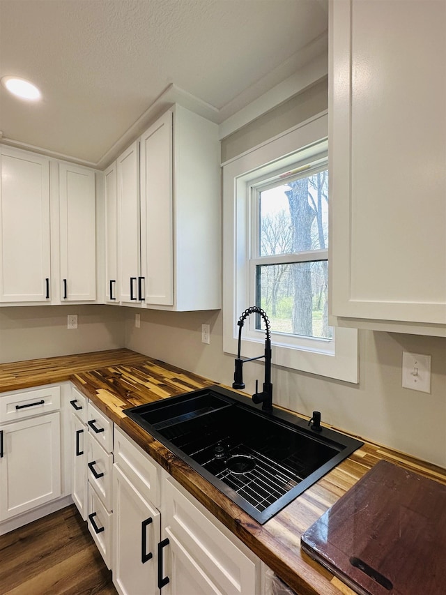 kitchen featuring white cabinetry, a sink, and butcher block counters