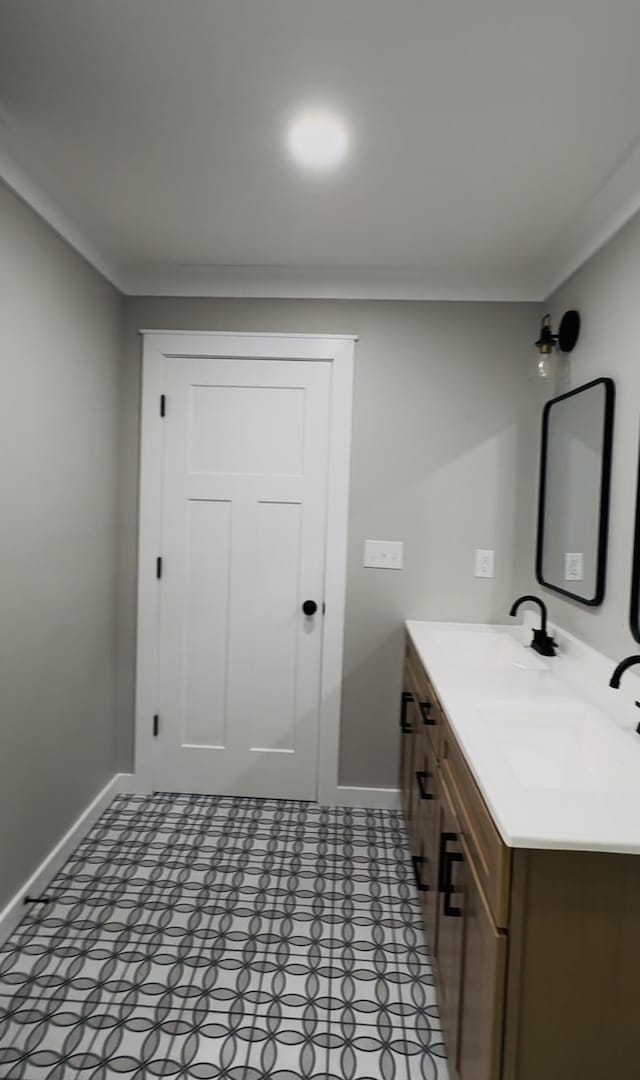 bathroom with baseboards, crown molding, and vanity