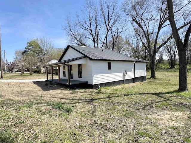 view of home's exterior with a lawn, metal roof, and covered porch