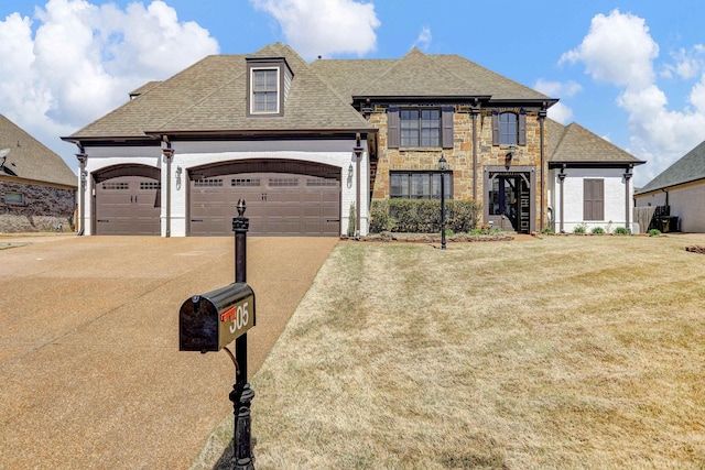 french country style house with concrete driveway, a garage, roof with shingles, and a front lawn