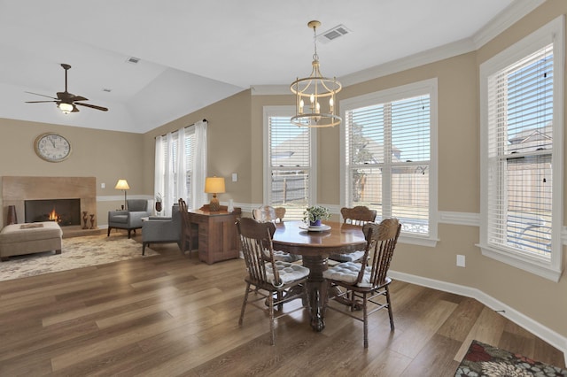 dining area with a high end fireplace, wood finished floors, ceiling fan with notable chandelier, and visible vents
