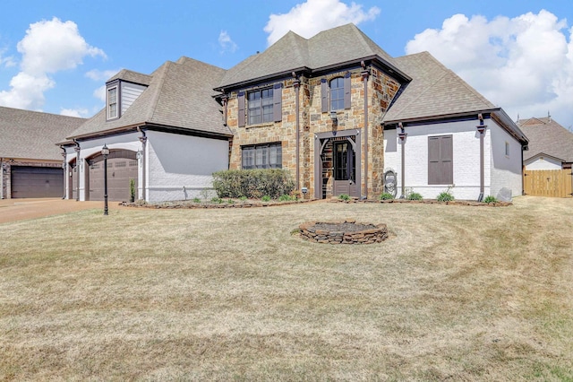 french provincial home with fence, an attached garage, concrete driveway, a front lawn, and roof with shingles