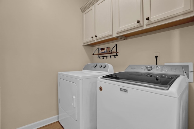 clothes washing area with independent washer and dryer, light wood-type flooring, cabinet space, and baseboards