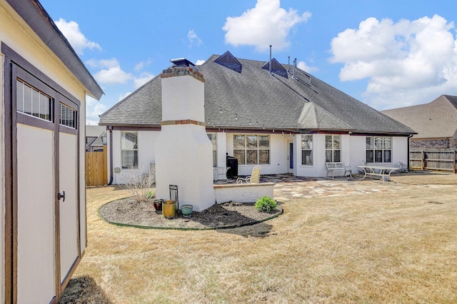 rear view of property featuring a patio area, a yard, fence, and roof with shingles
