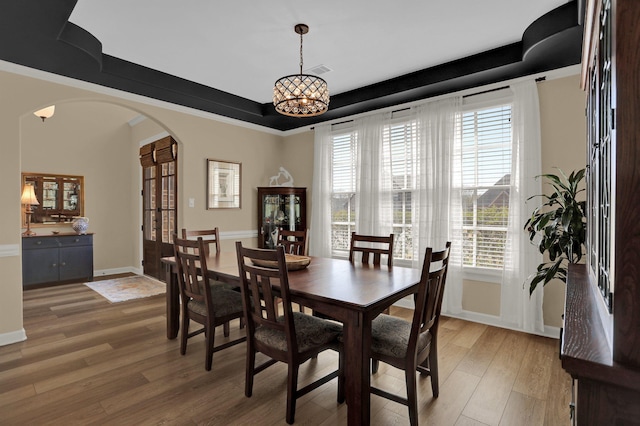 dining room with baseboards, arched walkways, visible vents, light wood-style flooring, and a notable chandelier