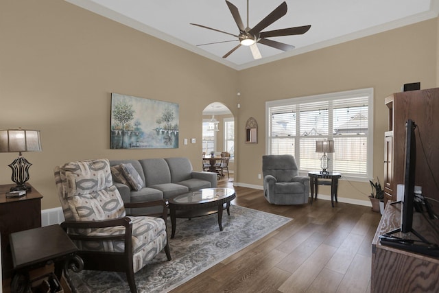 living area featuring a ceiling fan, plenty of natural light, arched walkways, and dark wood finished floors