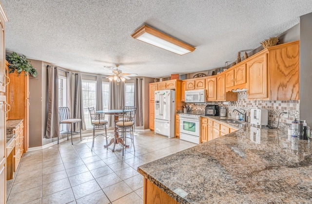 kitchen featuring light tile patterned flooring, backsplash, a sink, white appliances, and ceiling fan
