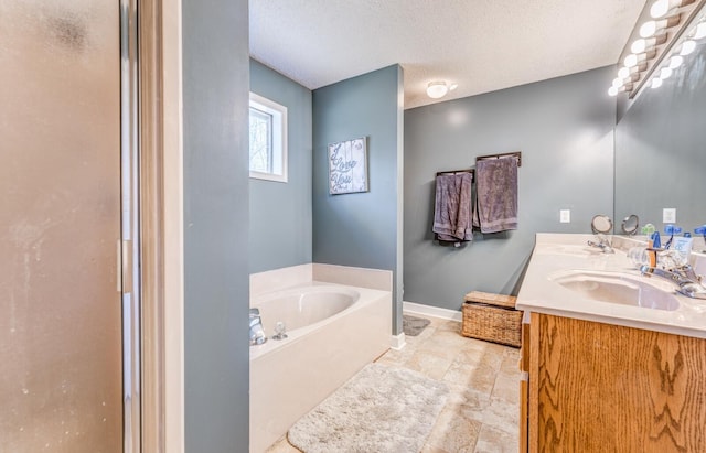 bathroom featuring vanity, a garden tub, a shower with door, a textured ceiling, and baseboards