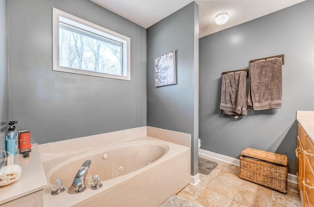 bathroom featuring a textured ceiling, baseboards, toilet, vanity, and a jetted tub