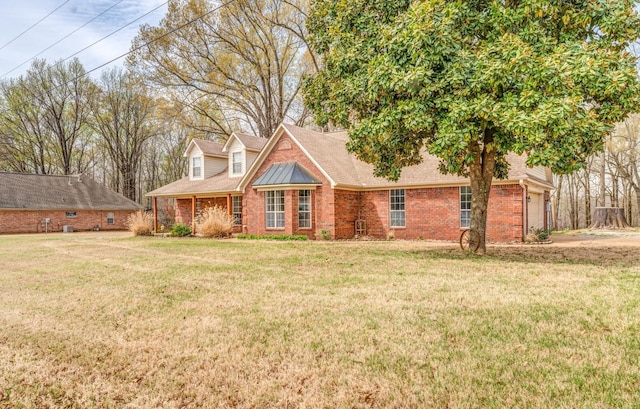 new england style home with brick siding, a garage, roof with shingles, and a front yard
