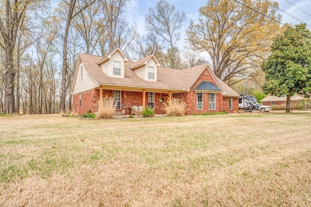 view of front facade with a front yard, brick siding, and roof with shingles
