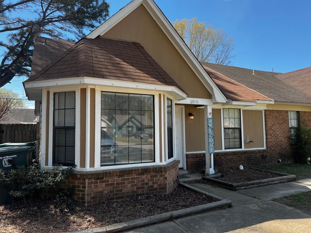 view of front of house featuring brick siding and roof with shingles