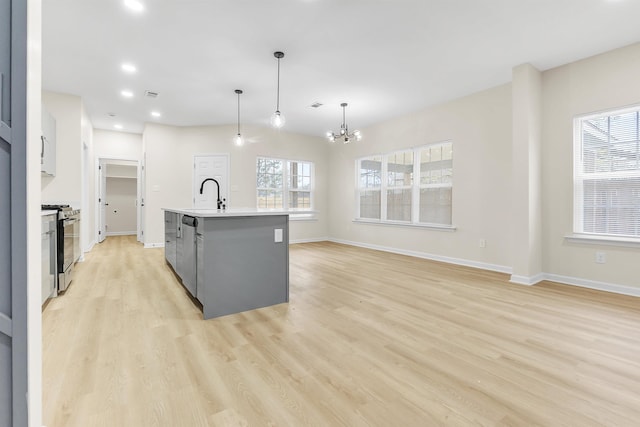 kitchen featuring a sink, a chandelier, light wood finished floors, stainless steel appliances, and plenty of natural light