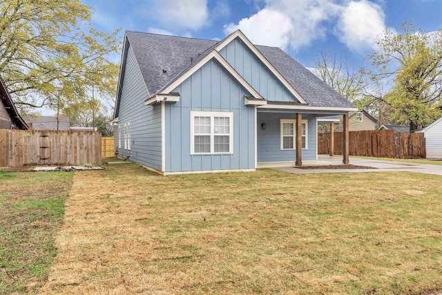 view of front of property with a front yard, fence, board and batten siding, and roof with shingles