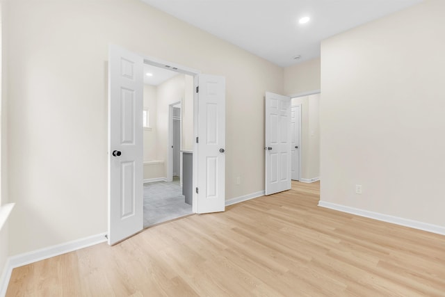 unfurnished bedroom with a spacious closet, baseboards, light wood-style floors, and recessed lighting