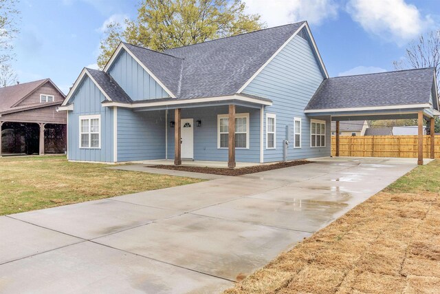 view of front of house with roof with shingles, a front yard, board and batten siding, and concrete driveway