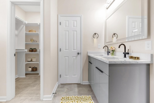 bathroom with double vanity, baseboards, and a sink