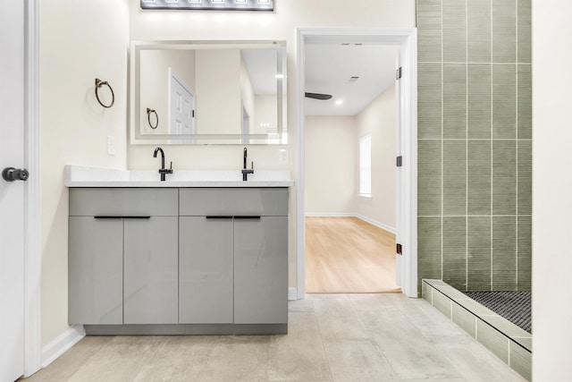 full bath with baseboards, tiled shower, tile patterned floors, and vanity