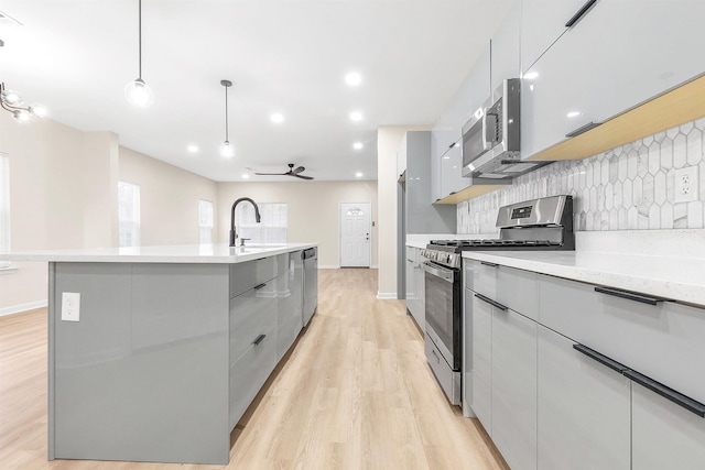 kitchen featuring gray cabinets, stainless steel appliances, tasteful backsplash, and modern cabinets