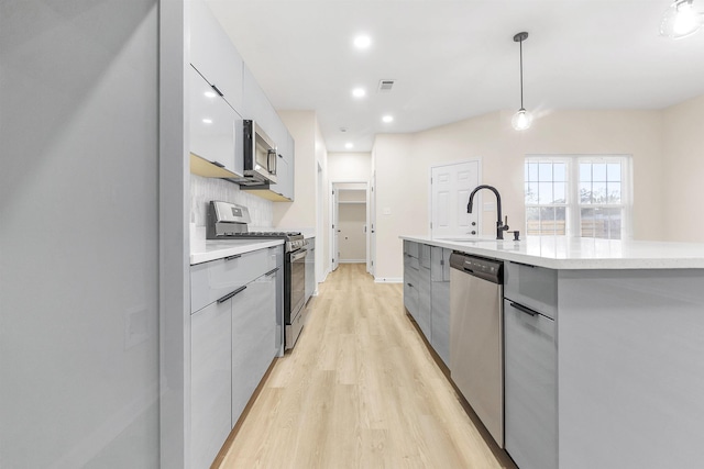 kitchen featuring light countertops, a sink, modern cabinets, and stainless steel appliances