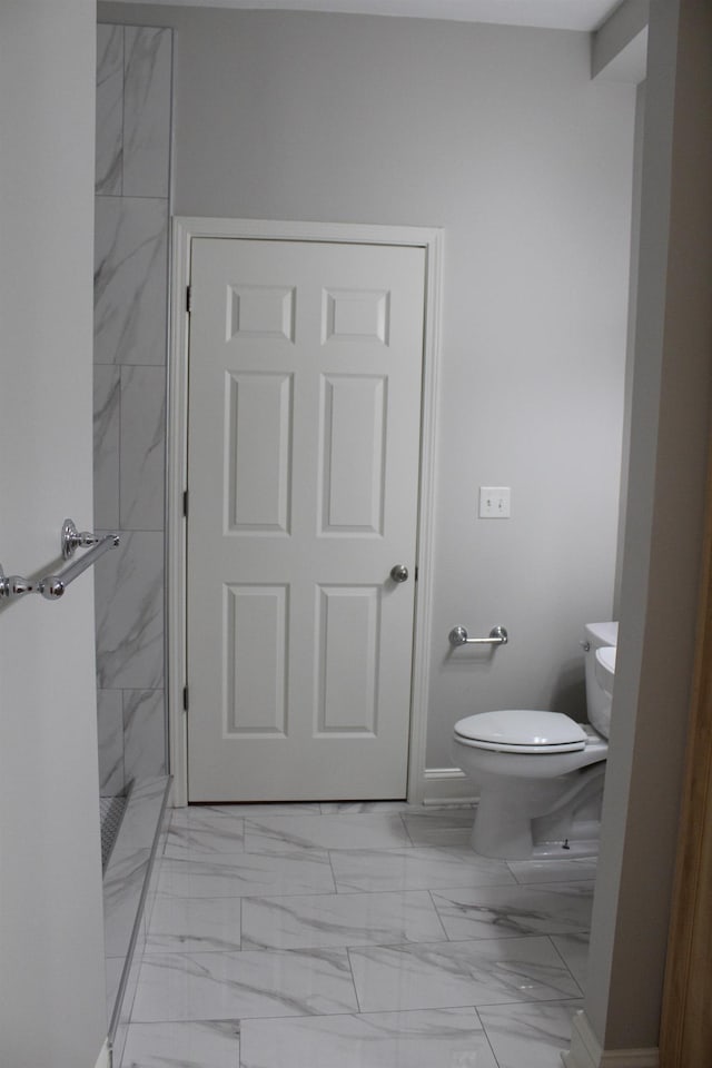 bathroom featuring marble finish floor, toilet, baseboards, and a stall shower