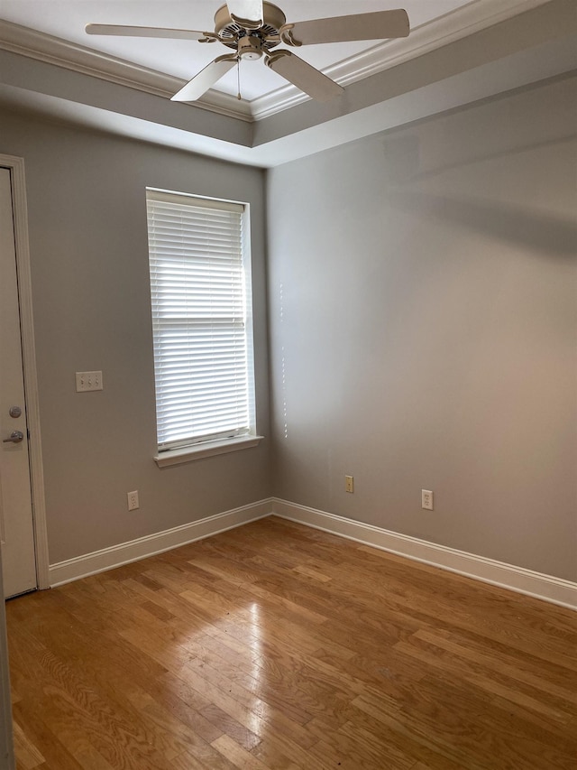 spare room featuring ceiling fan, baseboards, crown molding, and light wood-type flooring
