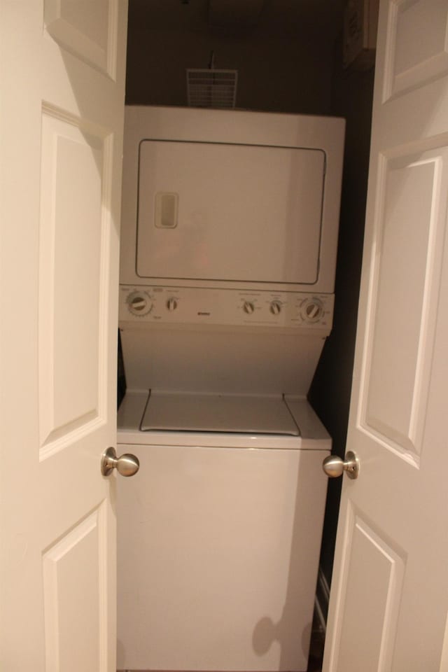 clothes washing area with stacked washer and clothes dryer and laundry area