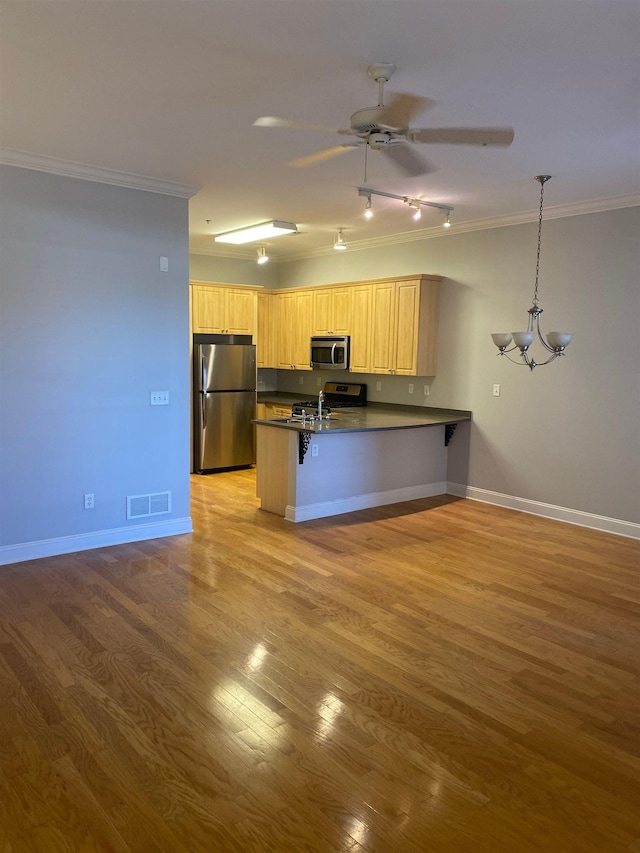 kitchen featuring a peninsula, dark countertops, visible vents, crown molding, and appliances with stainless steel finishes