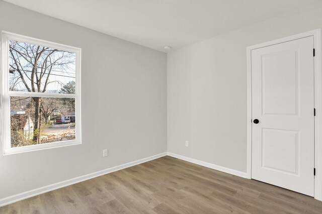 spare room featuring baseboards and wood finished floors