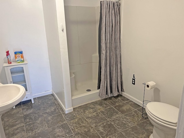 full bathroom featuring toilet, a stall shower, and baseboards