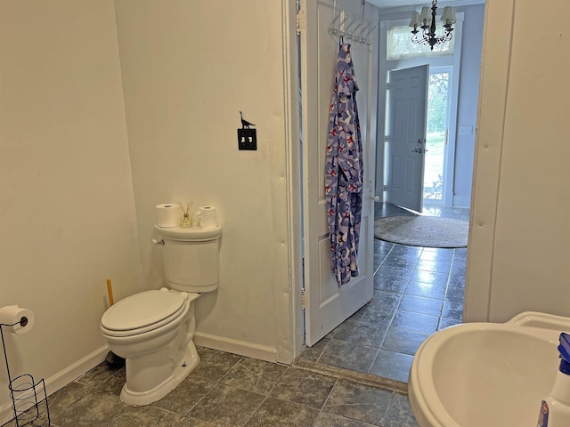 bathroom featuring baseboards, a notable chandelier, toilet, and a sink