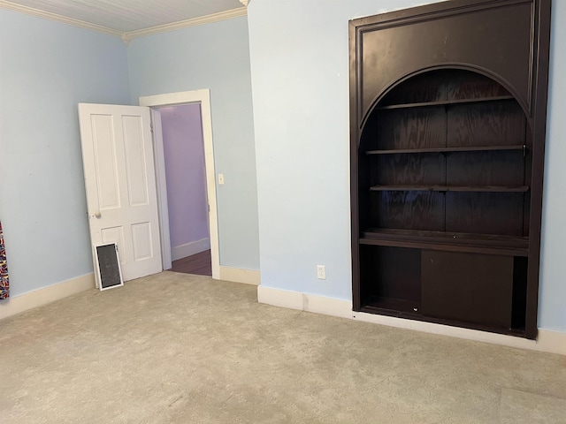 unfurnished room with baseboards, crown molding, carpet floors, and built in shelves