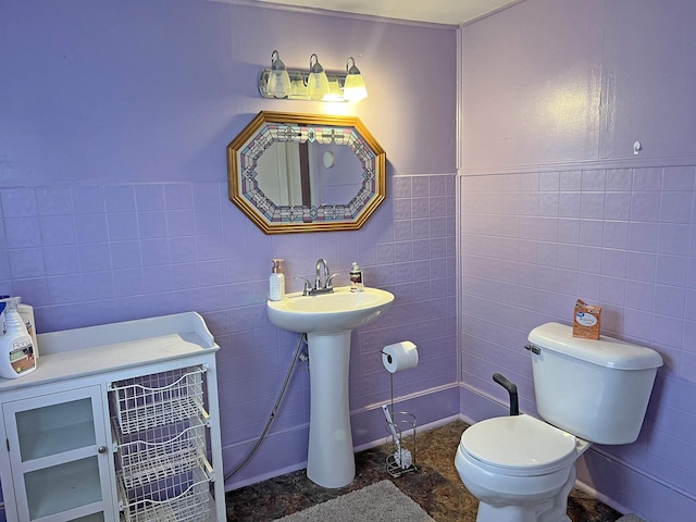 half bath featuring toilet and tile walls