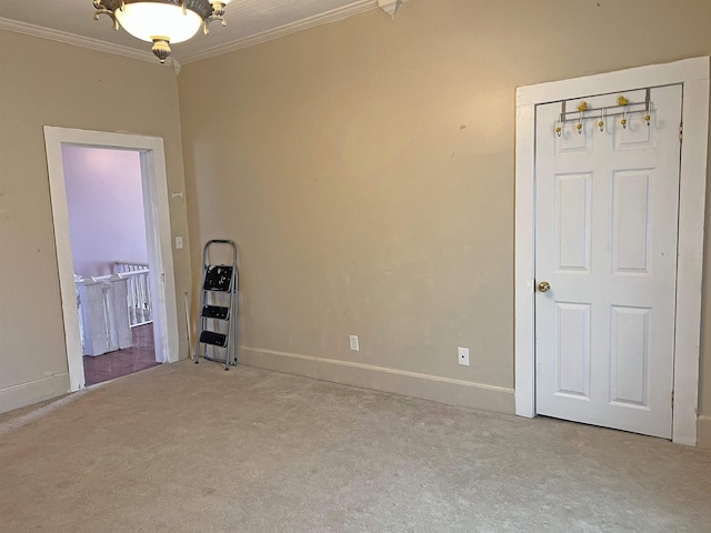 spare room featuring carpet floors, crown molding, and baseboards