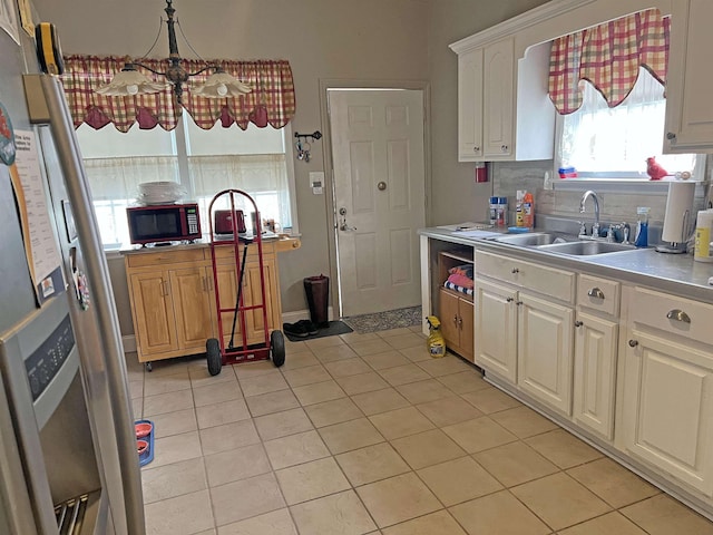 kitchen featuring light countertops, white cabinets, tasteful backsplash, a sink, and stainless steel fridge with ice dispenser